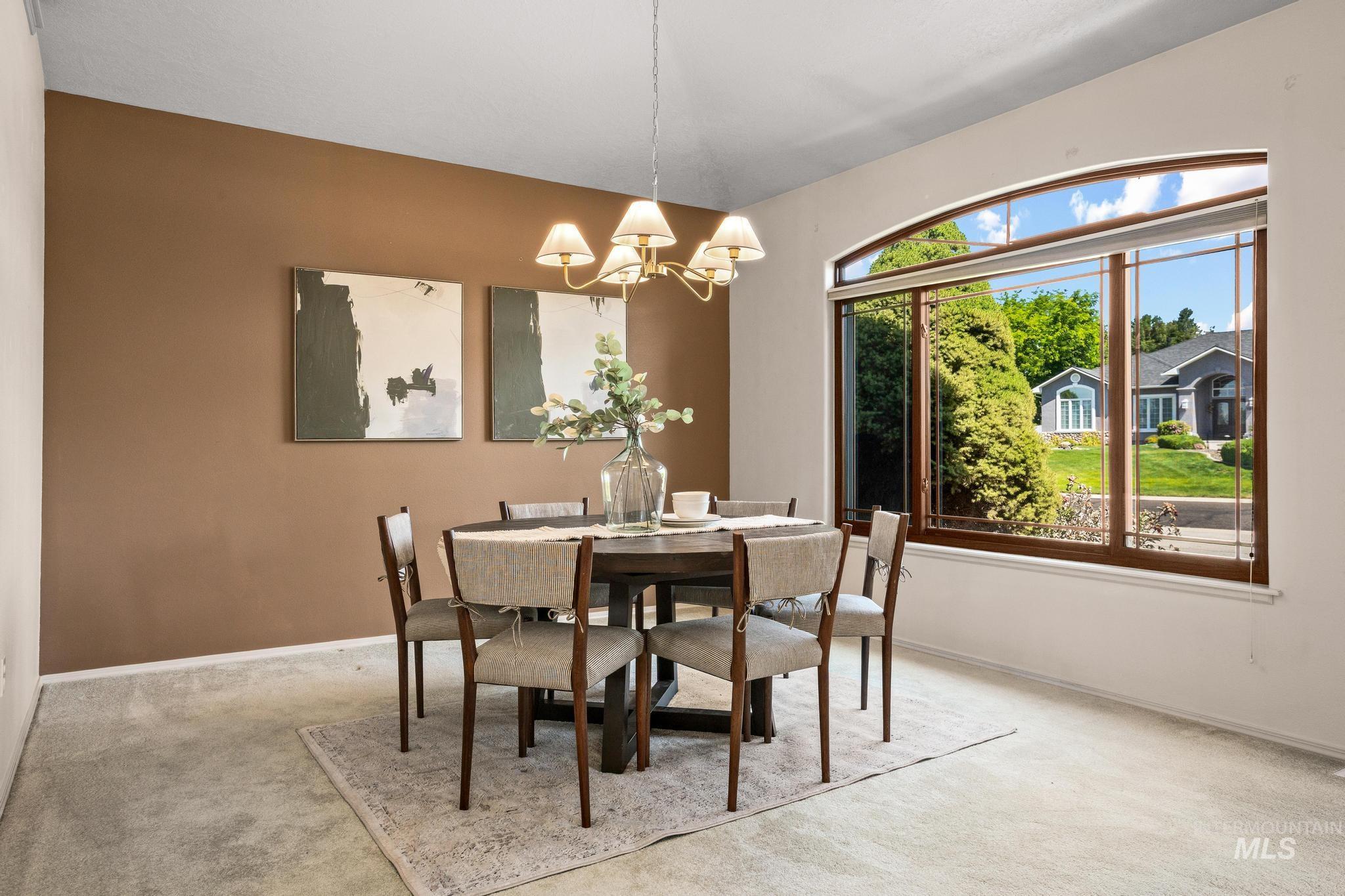 15181 Drury Way Caldwell, ID 83607 - Photo 6 of 49 Formal dining space featuring a large arched window with brown framing, neutral carpeting, and a contrasting accent wall