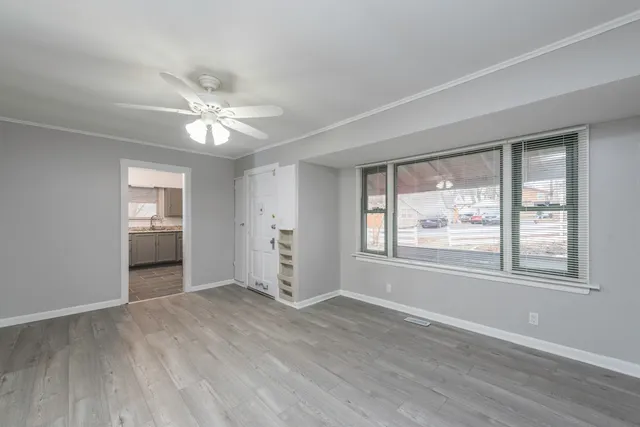 an empty room with wooden floor fan and windows