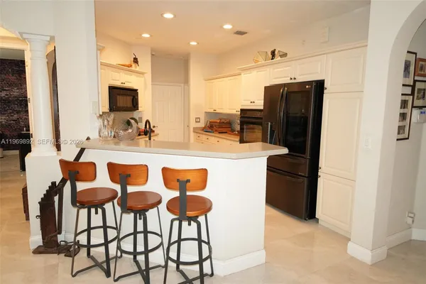 a kitchen with stainless steel appliances kitchen island granite countertop a table chairs and a refrigerator