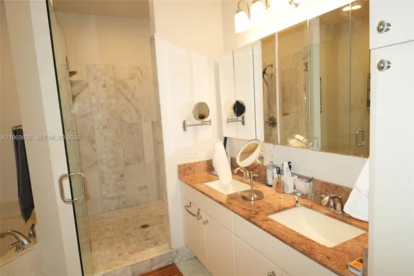 a bathroom with a granite countertop sink a mirror and shower