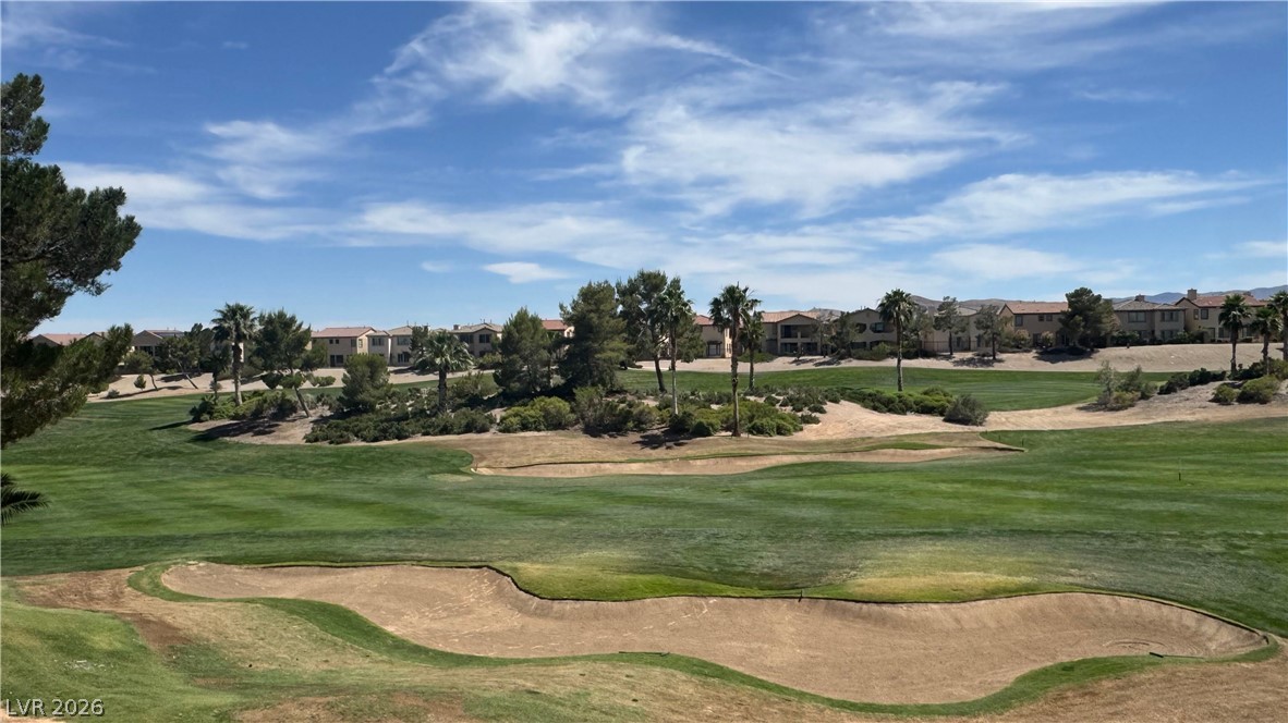 87 Tall Ruff Drive Las Vegas, NV 89148 - Photo 38 of 71 Green fairways and sandy bunkers create a picturesque golf course view with distant homes under a clear sky.