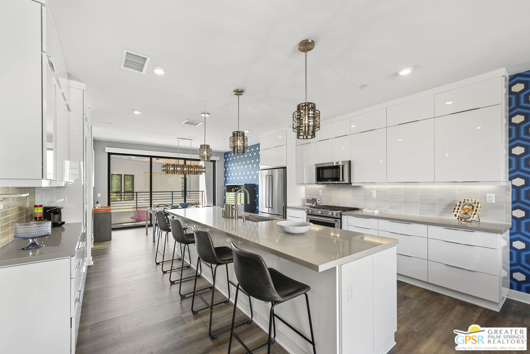 467 Huddle Spgs Way Palm Springs, CA 92264 - Photo 14 of 48 a kitchen with stainless steel appliances kitchen island a white table chairs and a wooden floor
