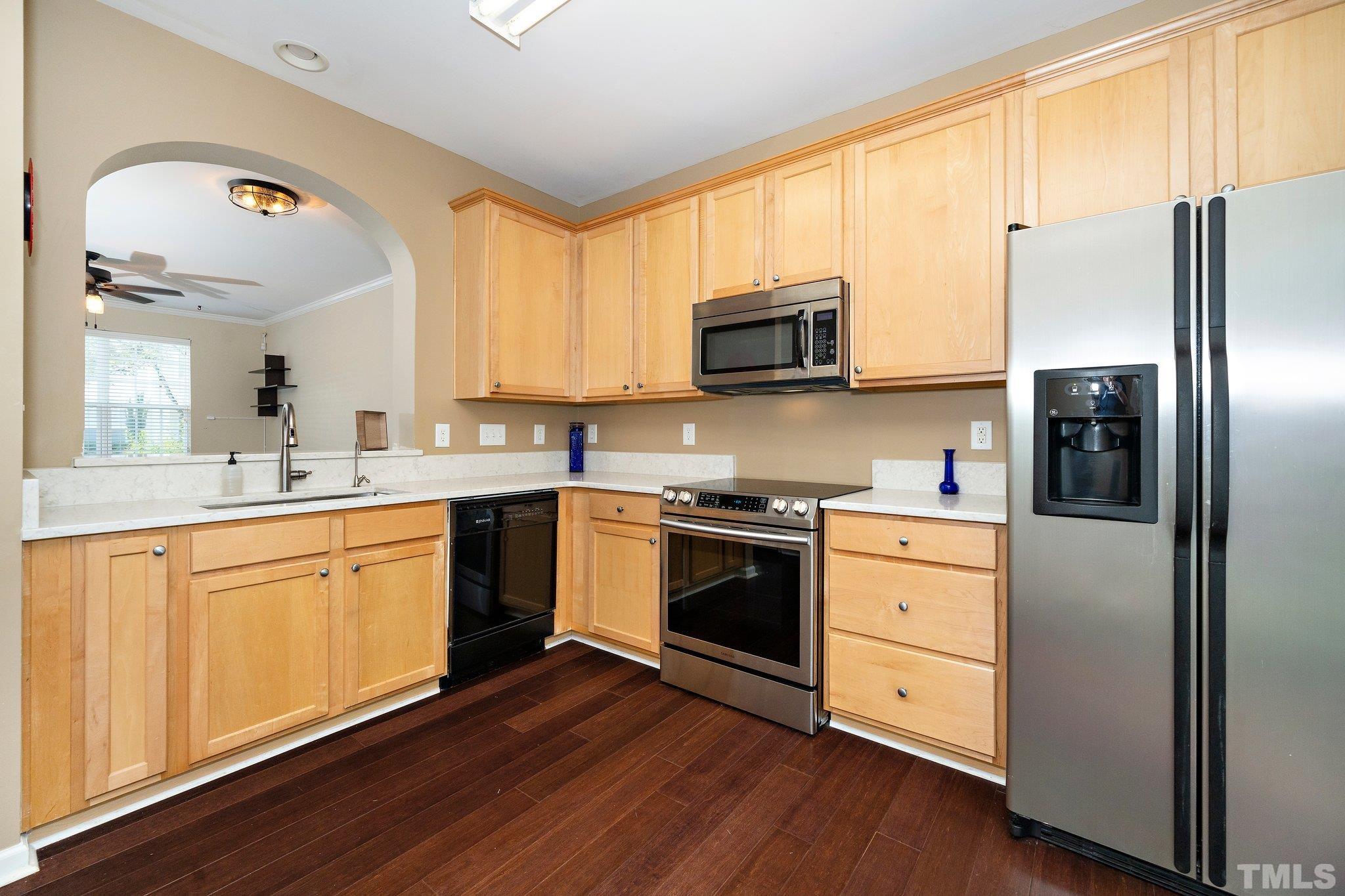 4114 Brenmar Lane Durham, NC 27713 - Photo 6 of 13 a kitchen with stainless steel appliances white cabinets a sink a stove a microwave and wooden floors