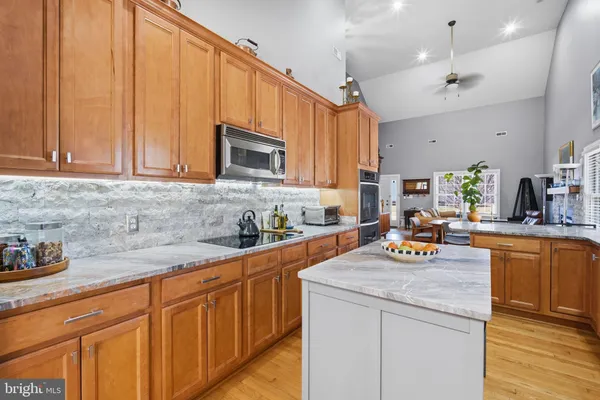 a kitchen with stainless steel appliances granite countertop a sink dishwasher stove and microwave with wooden cabinets