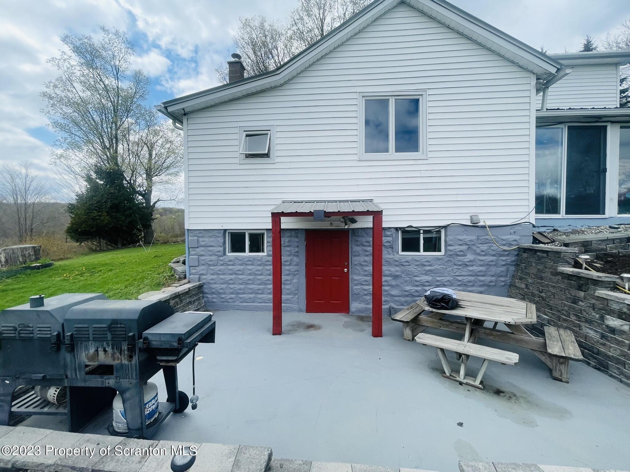 176 Stack Road Thompson, PA 18465 - Photo 34 of 53 a backyard of a house with barbeque oven table and chairs