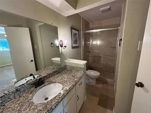 a bathroom with a granite countertop sink toilet and shower