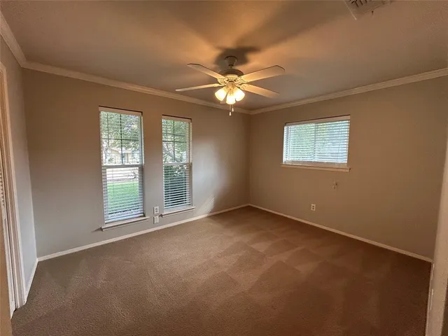 an empty room with chandelier fan and windows