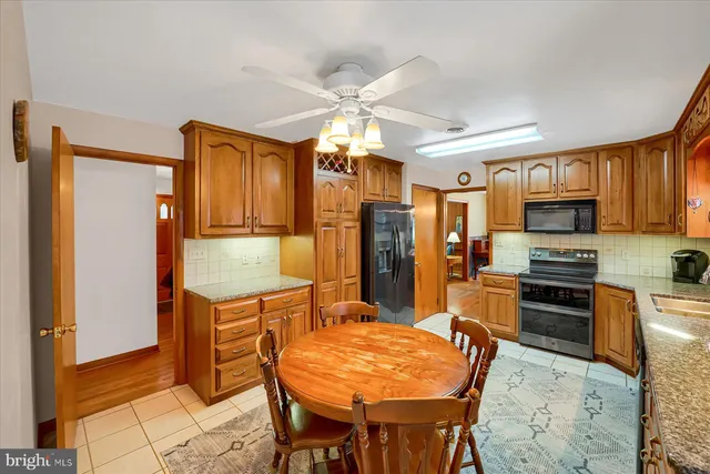 a kitchen with stainless steel appliances granite countertop a stove top oven a refrigerator a sink dishwasher and a dining table with wooden floor