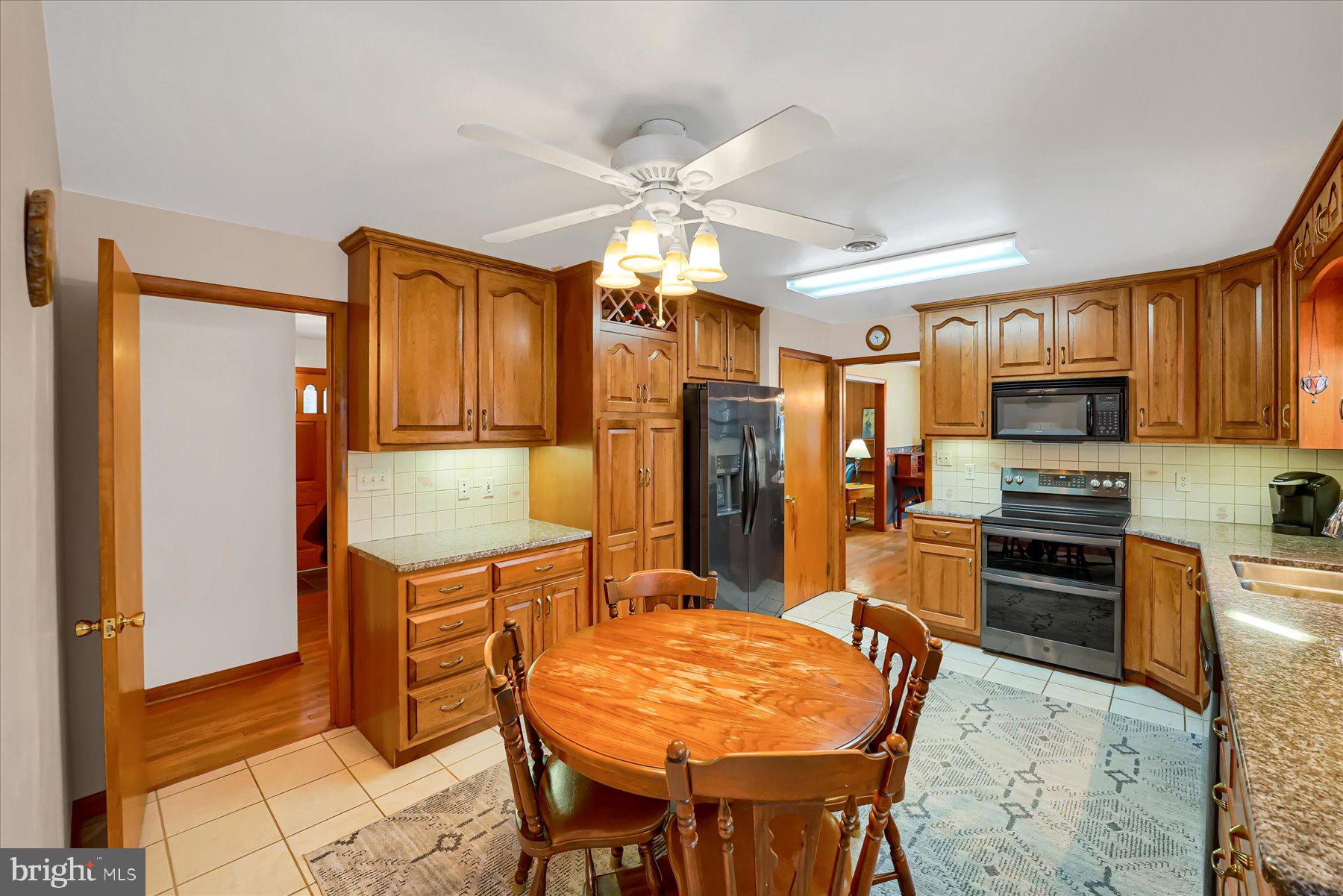 1105 Outer Drive State College, PA 16801 - Photo 15 of 44 a kitchen with stainless steel appliances granite countertop a stove top oven a refrigerator a sink dishwasher and a dining table with wooden floor