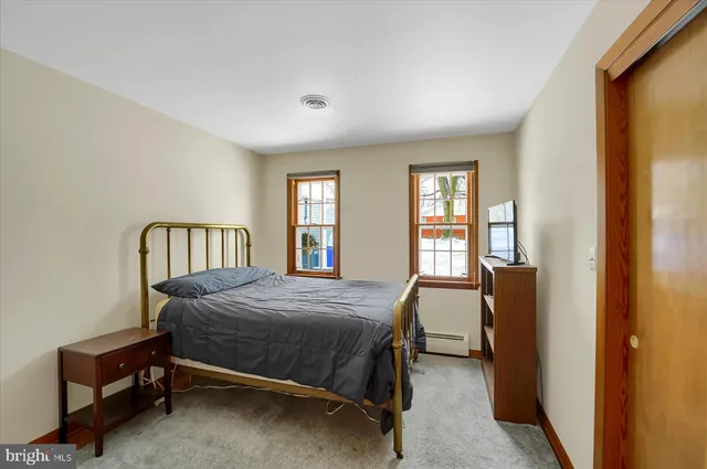 a bedroom with a bed chair and windows