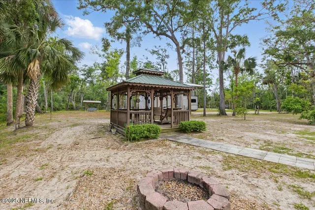 a view of a wooden house with a yard and large trees