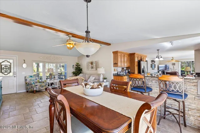 a view of a dining room and livingroom with furniture wooden floor a rug a painting and a chandelier