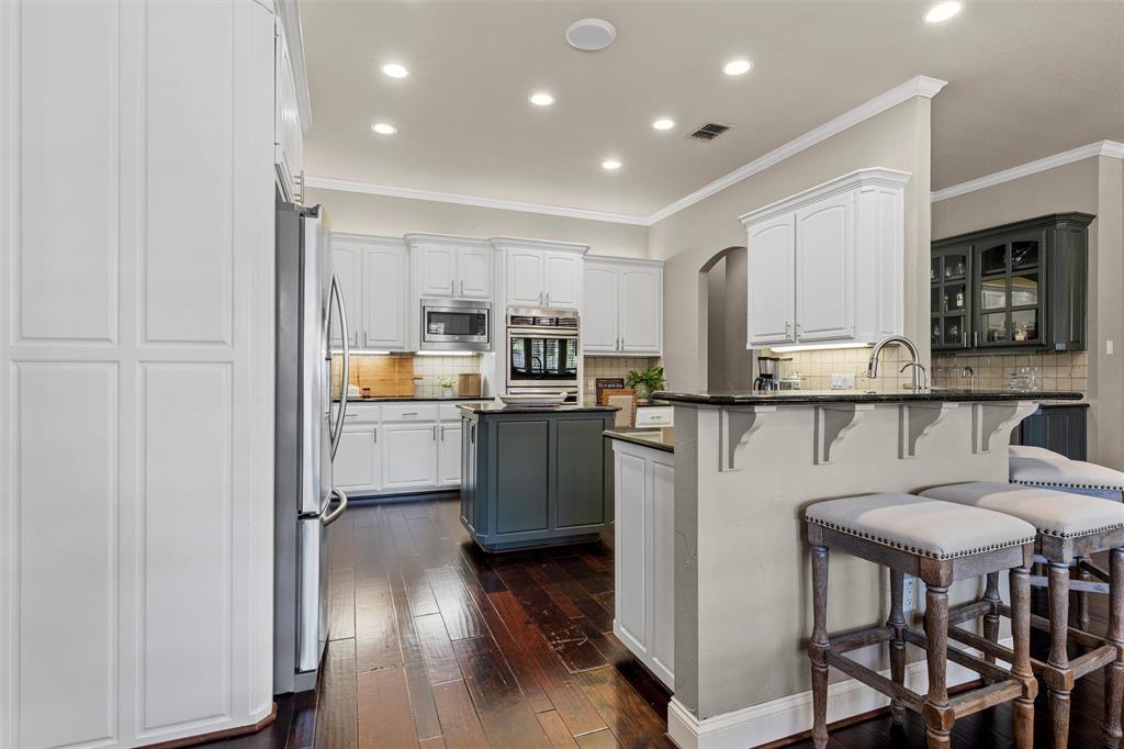 2030 Rustic Trail Waco, TX 76657 - Photo 8 of 40 a kitchen with kitchen island granite countertop wooden floors and stainless steel appliances