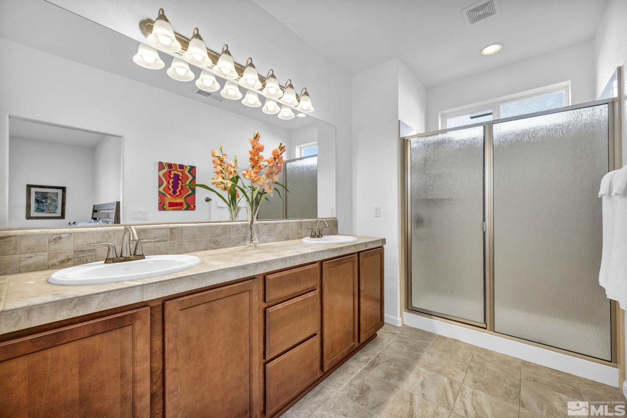 2197 Berkich Court Reno, NV 89521 - Photo 22 of 40 a bathroom with a granite countertop sink a large mirror and a shower