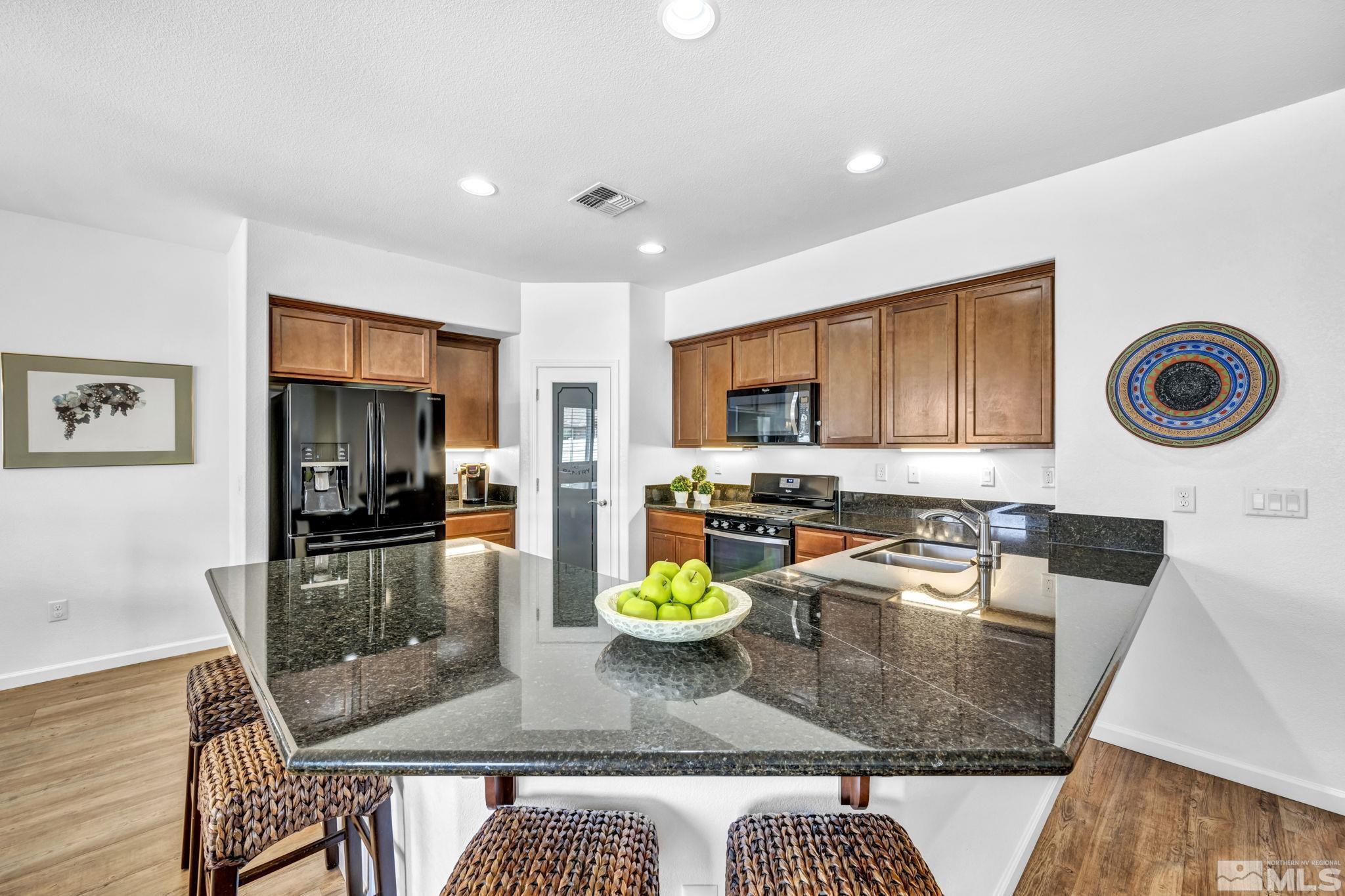 2197 Berkich Court Reno, NV 89521 - Photo 4 of 40 a kitchen with stainless steel appliances granite countertop a refrigerator a stove top oven a dining table and chairs with wooden floor