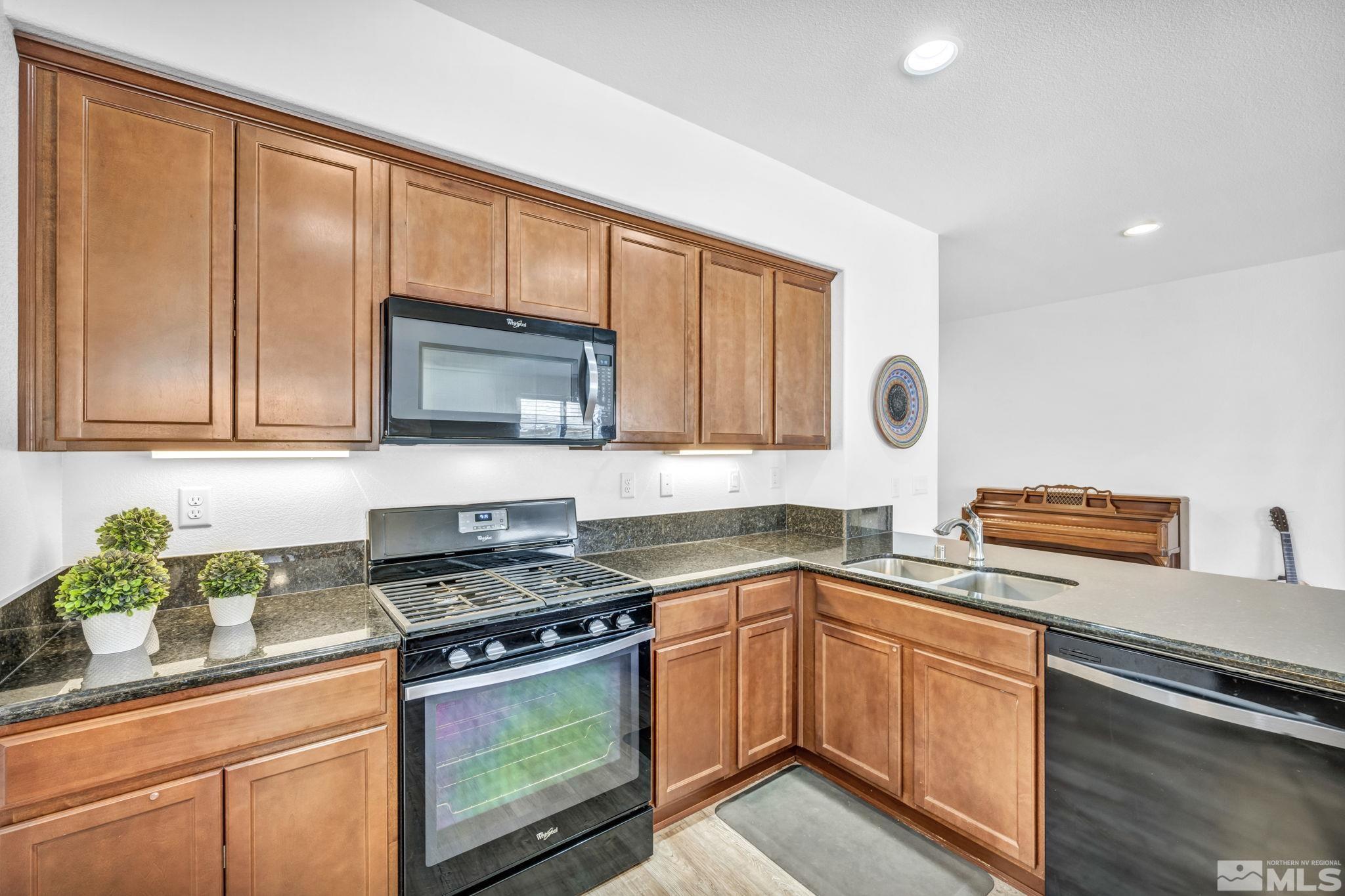 2197 Berkich Court Reno, NV 89521 - Photo 8 of 40 a kitchen with stainless steel appliances granite countertop a stove a sink dishwasher and microwave with wooden cabinets