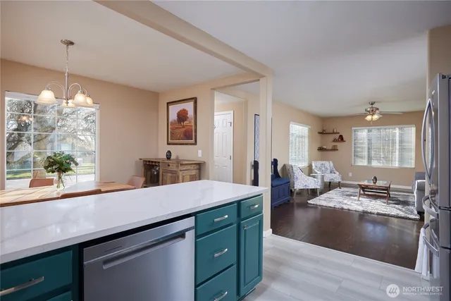 a living room with stainless steel appliances kitchen island granite countertop a sink dishwasher and a fireplace with wooden floor