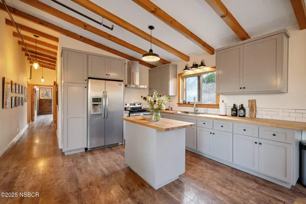 a kitchen with stainless steel appliances granite countertop a refrigerator a sink dishwasher a stove and white countertops with wooden floor