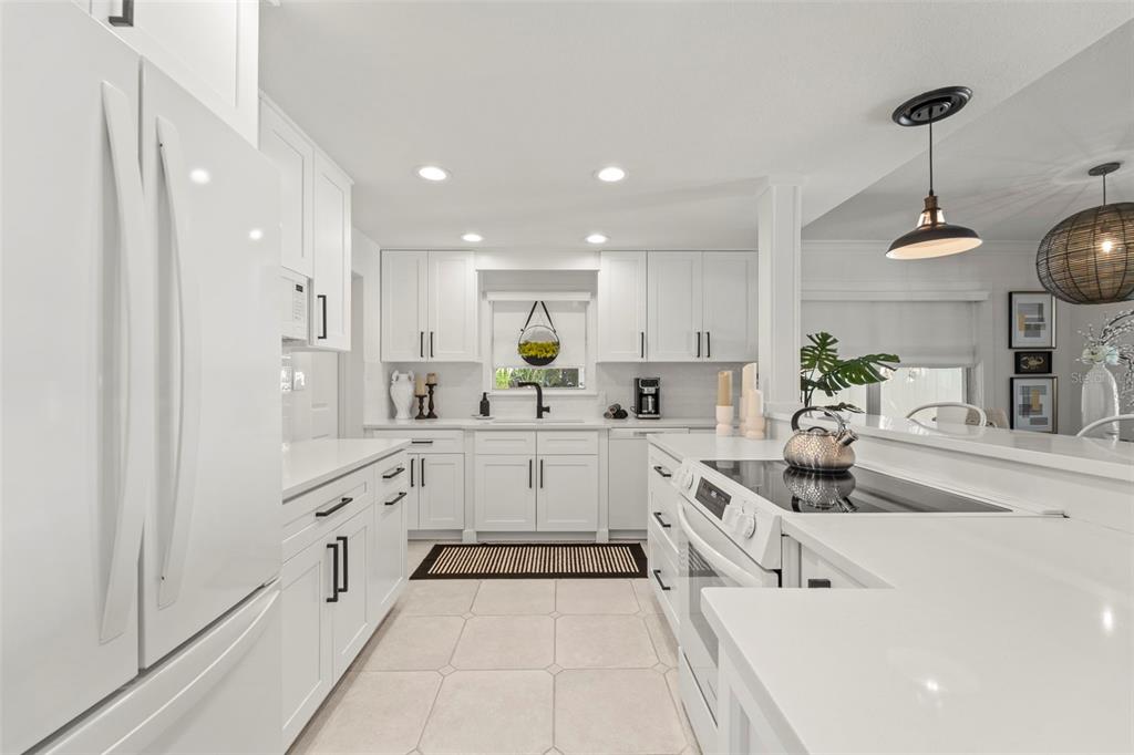 402 161st Avenue Redington Beach, FL 33708 - Photo 18 of 55 a large white kitchen with stainless steel appliances granite countertop lots of white cabinets a sink and dishwasher