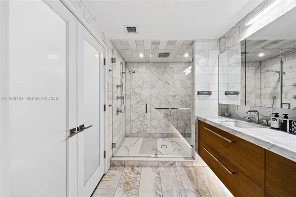 a bathroom with a sink a toilet a mirror and shower