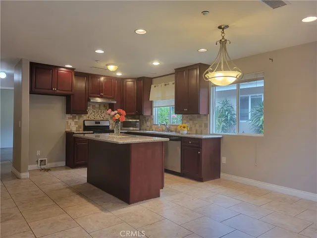 a kitchen with kitchen island granite countertop a stove and a sink