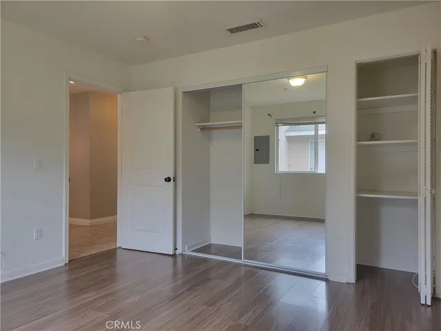 an empty room with wooden floor & closet and windows