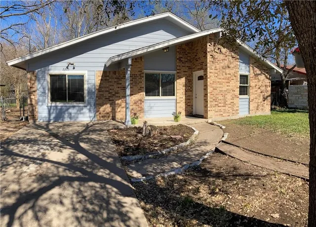 a backyard of a house with large trees and brick wall