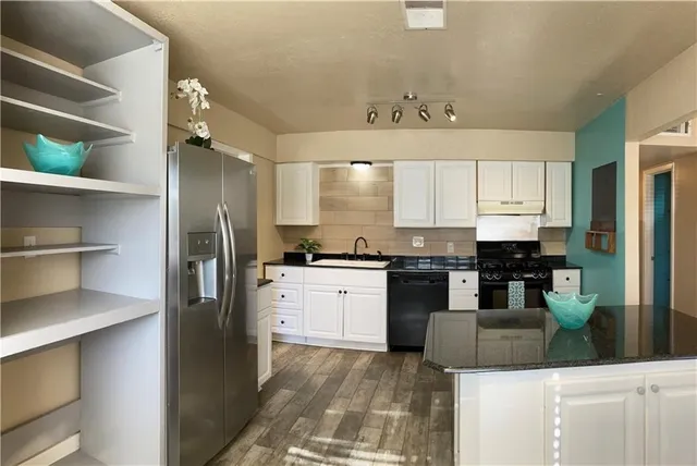 a kitchen with granite countertop a sink a stove and cabinets