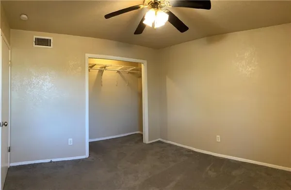 an empty room with a chandelier fan and closet