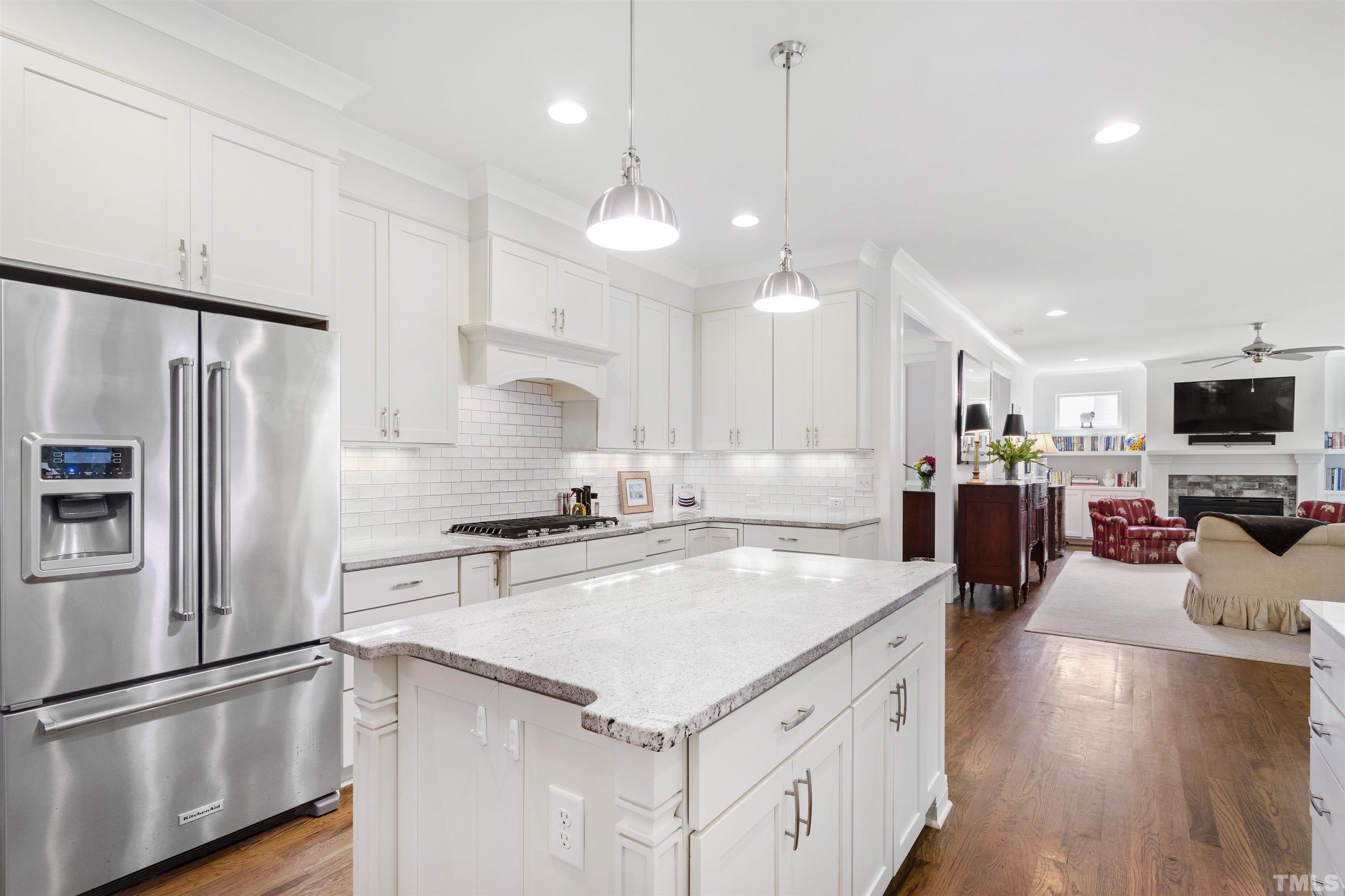 3205 Plantation Road Raleigh, NC 27609 - Photo 12 of 39 a kitchen with a refrigerator a sink dishwasher a oven and a dining table with wooden floor