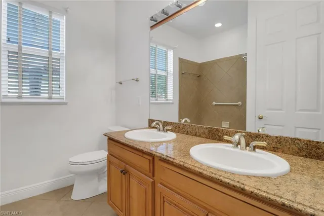 a bathroom with a granite countertop sink a toilet and a mirror