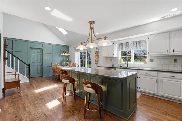 a kitchen with stainless steel appliances granite countertop a sink a stove a dining table and chairs