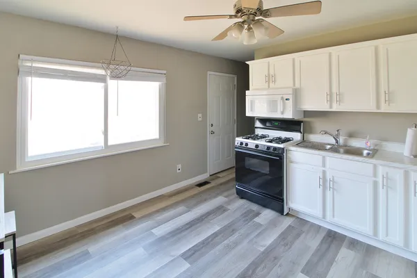 a kitchen with stainless steel appliances a stove a sink and white cabinets