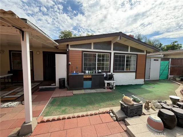 a view of a backyard with table and chairs potted plants and a large tree