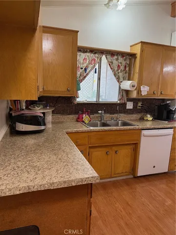 a room with kitchen island granite countertop a sink a stove and a wooden floors