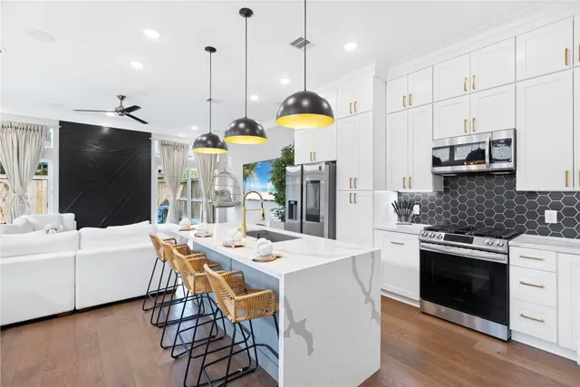 a kitchen with stainless steel appliances kitchen island granite countertop a stove a sink a refrigerator and a dining table with wooden floor