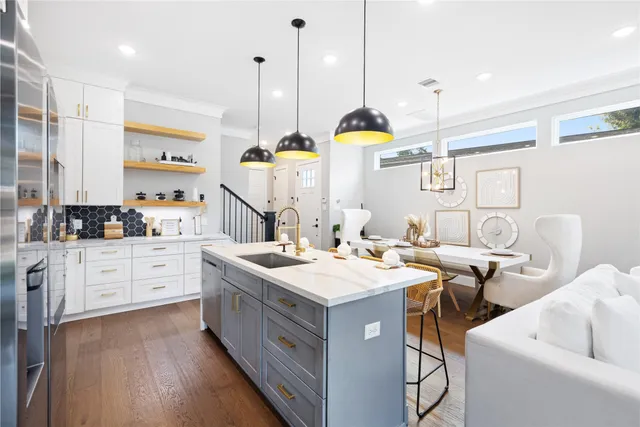 a kitchen with stainless steel appliances kitchen island granite countertop a stove a sink and white cabinets with wooden floor