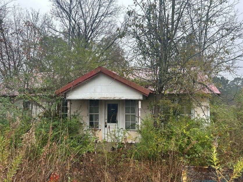 a view of house with yard and trees in the background