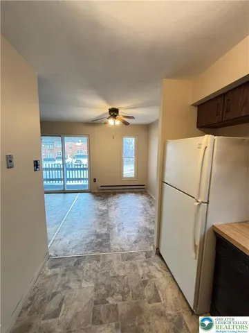 a view of a refrigerator in kitchen and an empty room