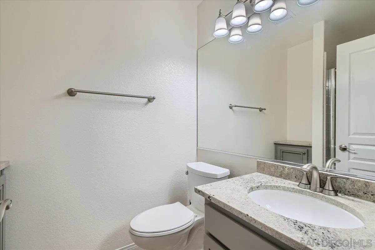 1382 Sparrow Road Carlsbad, CA 92011 - Photo 15 of 34 a bathroom with a granite countertop toilet sink and mirror
