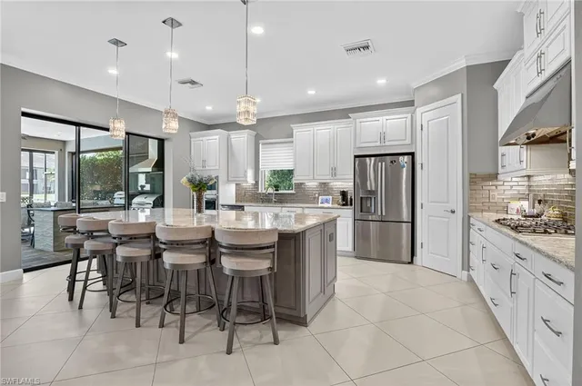 a kitchen with stainless steel appliances kitchen island granite countertop a table chairs and a sink