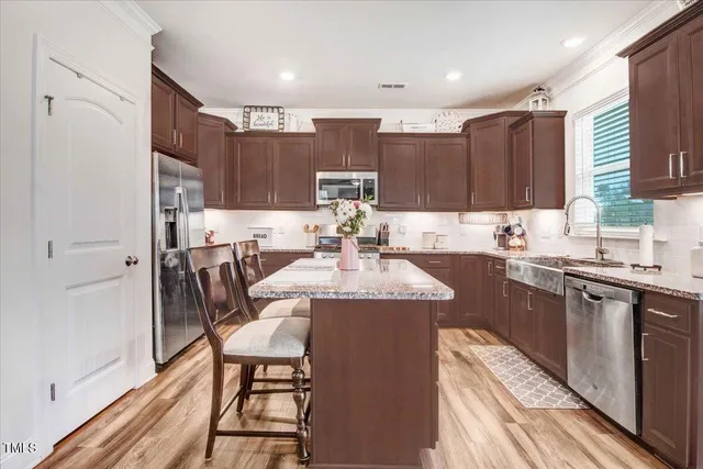 a kitchen with a sink a refrigerator and chairs