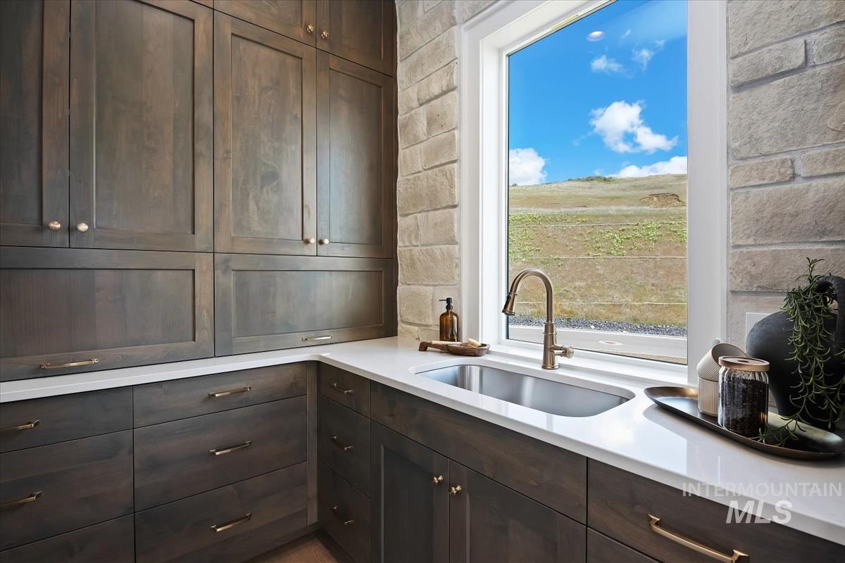 7615 Brown Way Eagle, ID 83714 - Photo 20 of 43 Dark wood-finish cabinetry, light stone accent wall, white countertop, stainless steel undermount sink, and a single-handle faucet