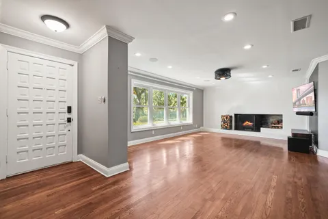 an empty room with wooden floor fireplace and windows