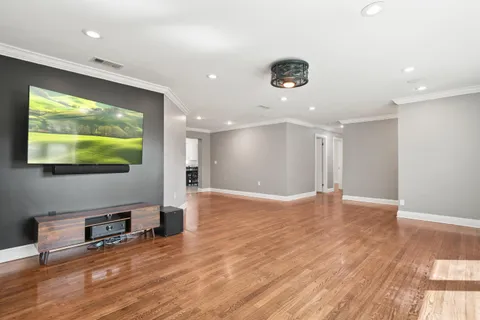 a view of an empty room with wooden floor and windows