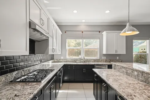 a kitchen with granite countertop a sink a center island stainless steel appliances and cabinets