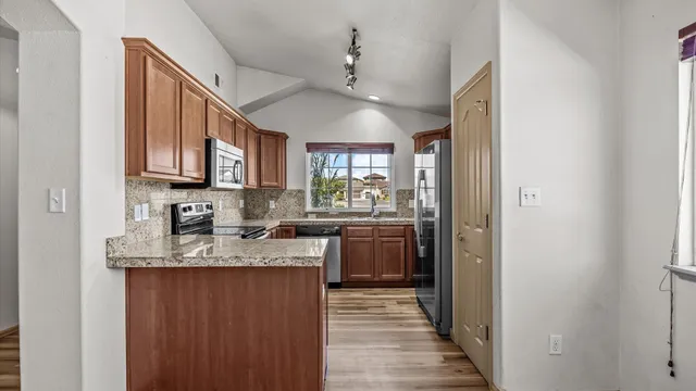 a kitchen with kitchen island granite countertop a sink cabinets and stainless steel appliances
