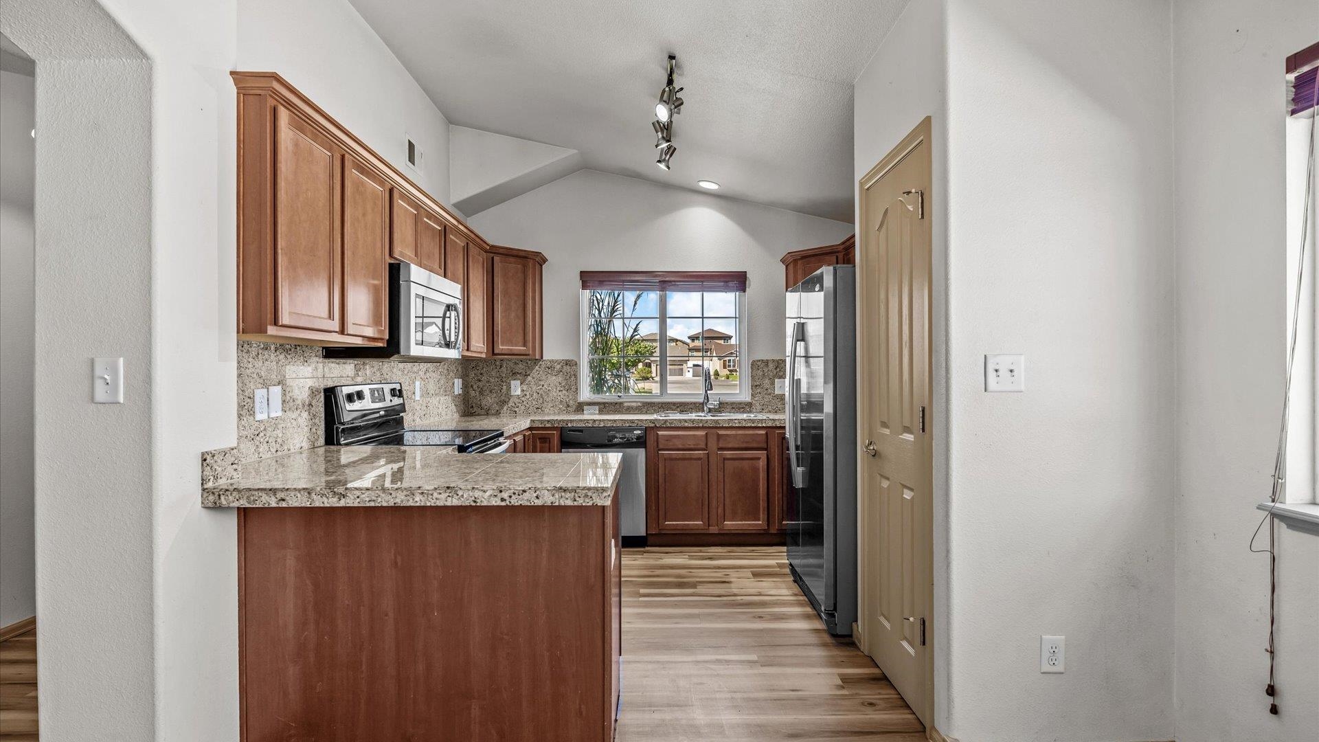 596 Sinatra Way Grand Junction, CO 81501 - Photo 5 of 20 a kitchen with kitchen island granite countertop a sink cabinets and stainless steel appliances