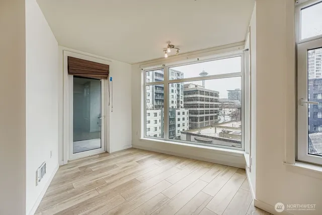 a view of an empty room with wooden floor and a window