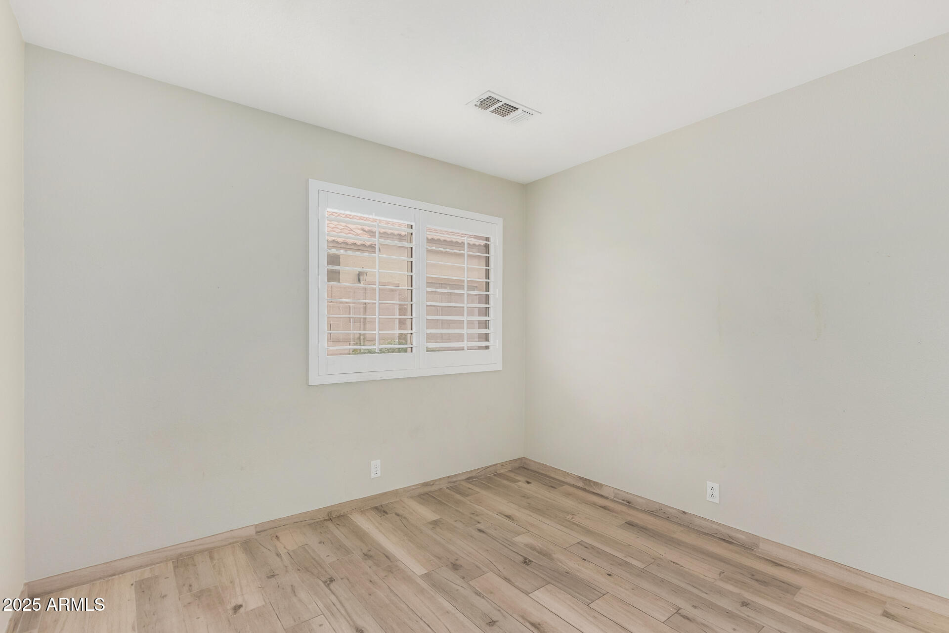 3942 East Agave Road Phoenix, AZ 85044 - Photo 19 of 30 an empty room with wooden floor and windows